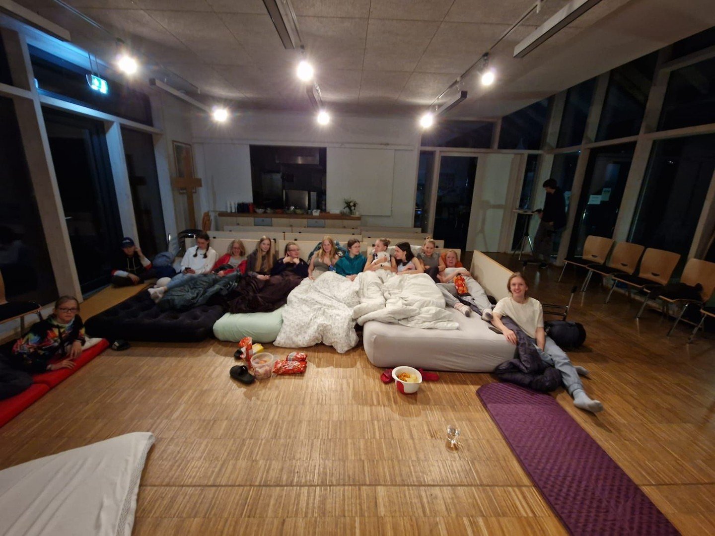 Menschen in einem hellen Raum, liegen und sitzen auf Matten am Boden.