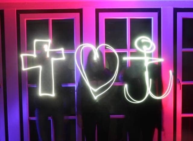 Leuchtende Neonschrift: Kreuz, Herz, „i“.