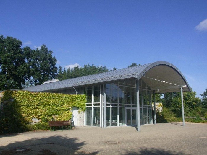 Modernes Gebäude mit geschwungenem Dach und Efeuwand.