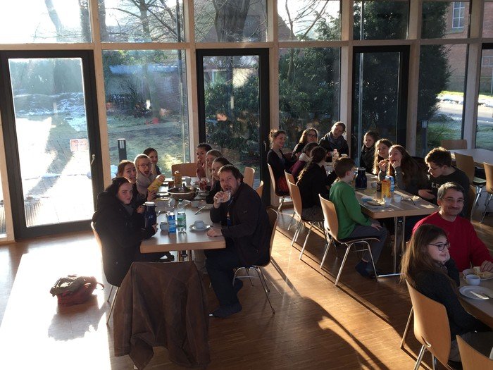 Eine Gruppe von Menschen sitzt an Tischen in einem modern eingerichteten Café.