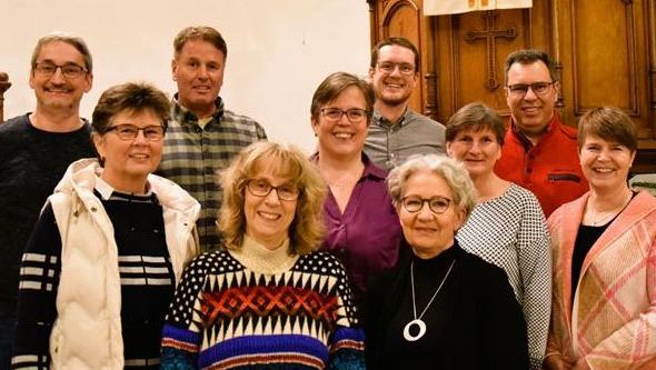 Große Gruppe von Erwachsenen posiert für ein Foto im Innenraum.