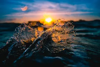 Sonnenuntergang über dem Wasser mit spritzenden Wellen, Nahaufnahme.