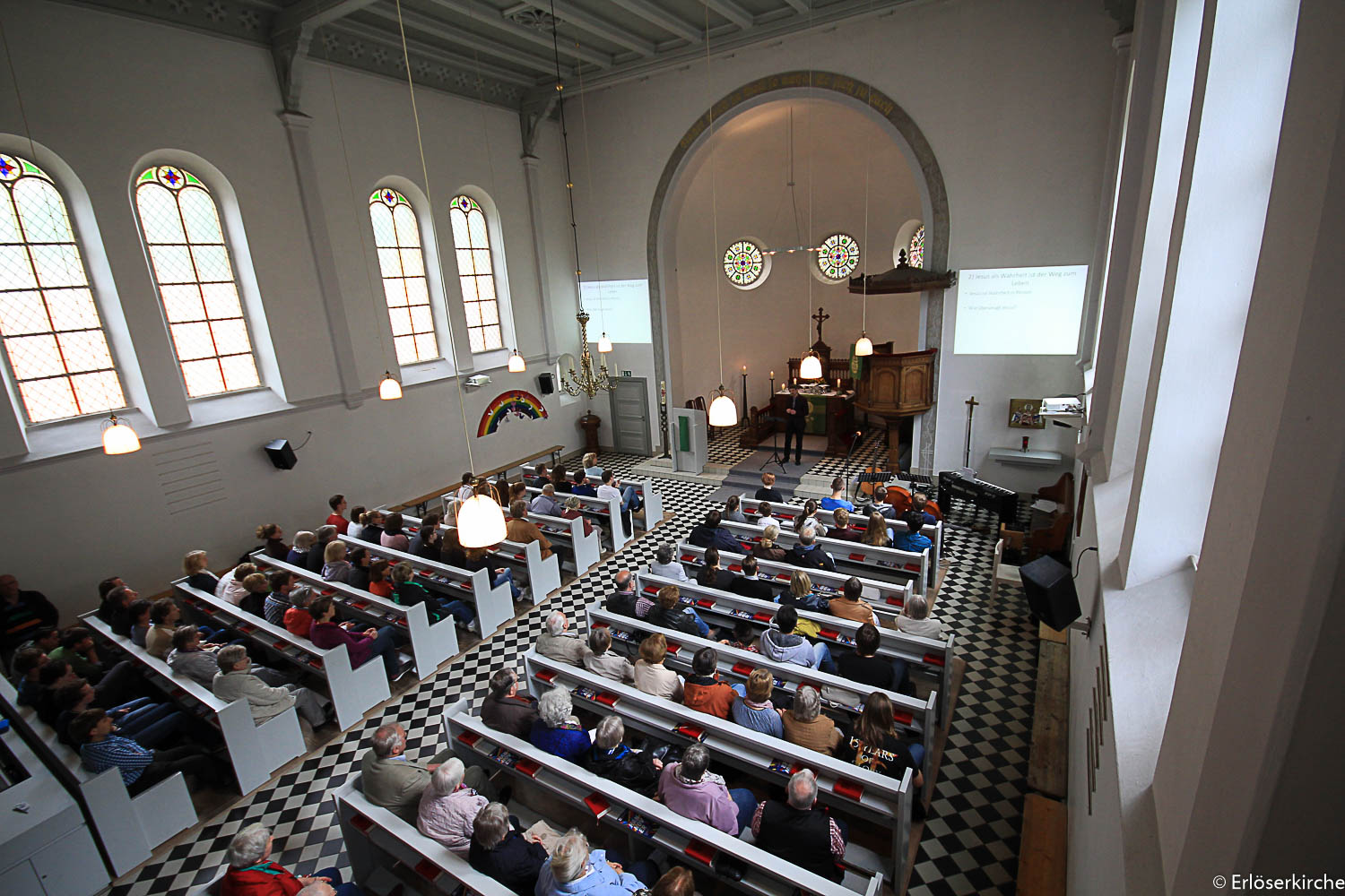 Kircheninnenraum von oben, gefüllt mit Gemeindemitgliedern in Reihen.