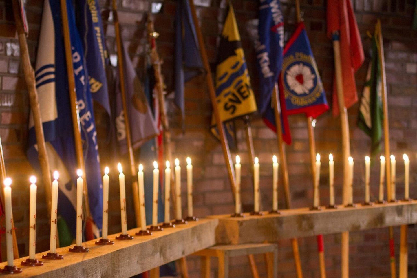 Kerzen in einem Kerzenständer mit Fahnen im Hintergrund.